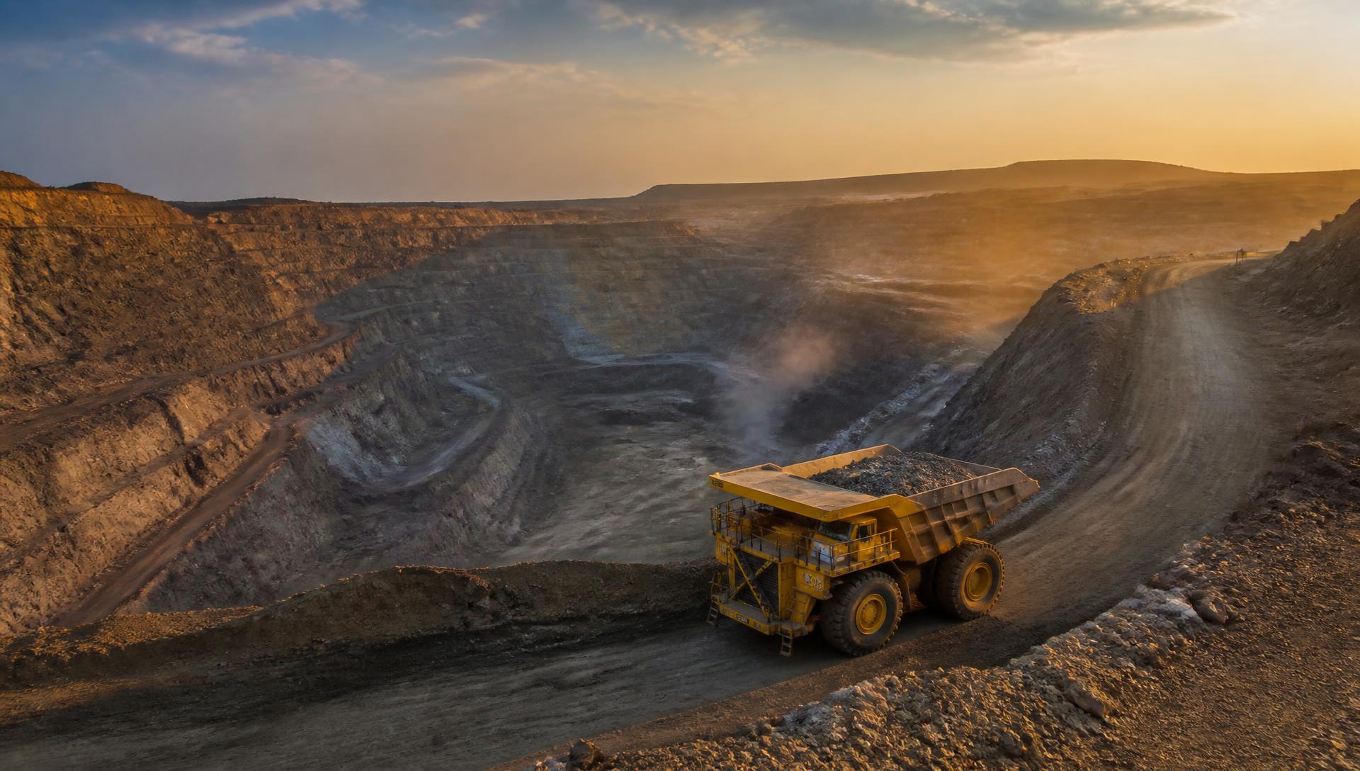 Mina a céu aberto com caminhão gigante de mineração ao amanhecer